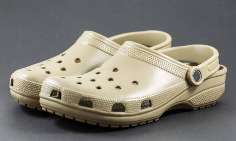 A pair of brown sandals with motif design isolated on black background.